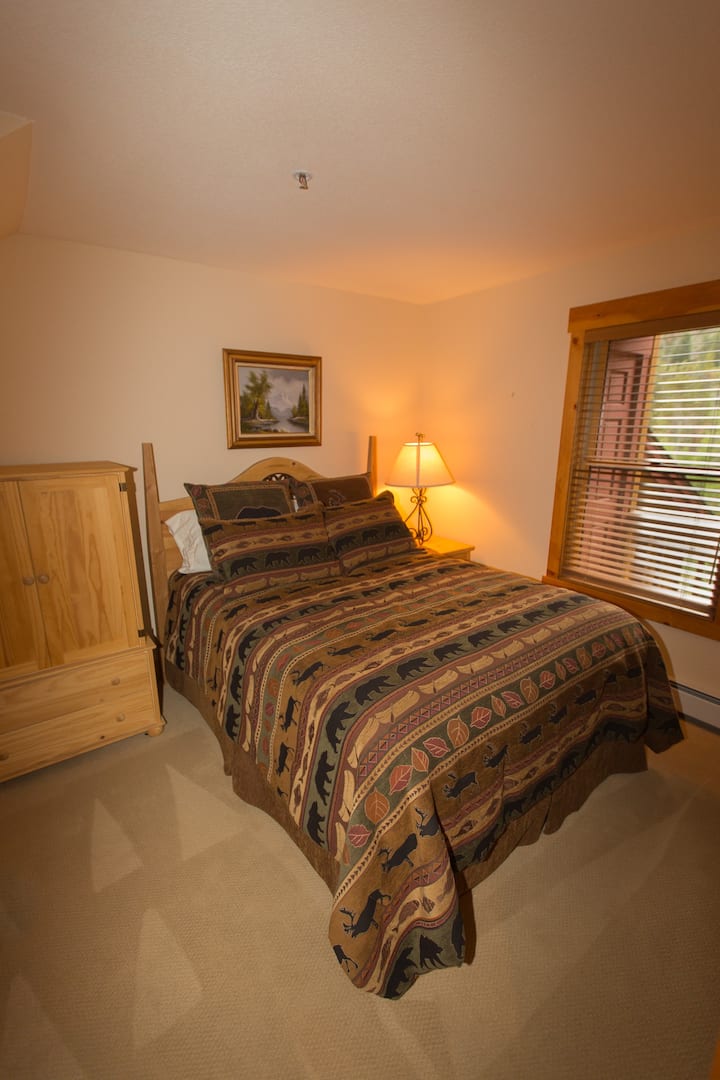 A bedroom with a bed, nightstand and lamp.